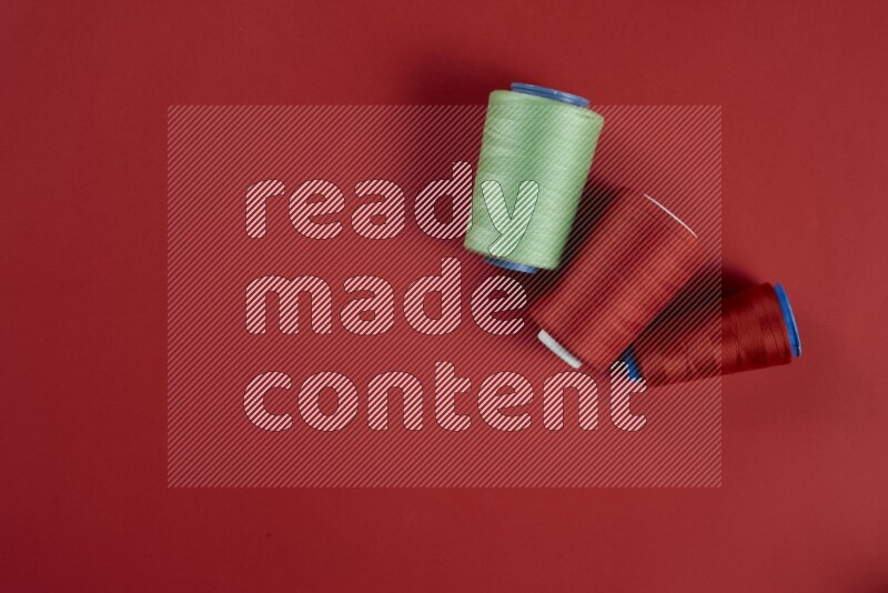 A green and red collection of sewing and tailoring tools arranged on a red background