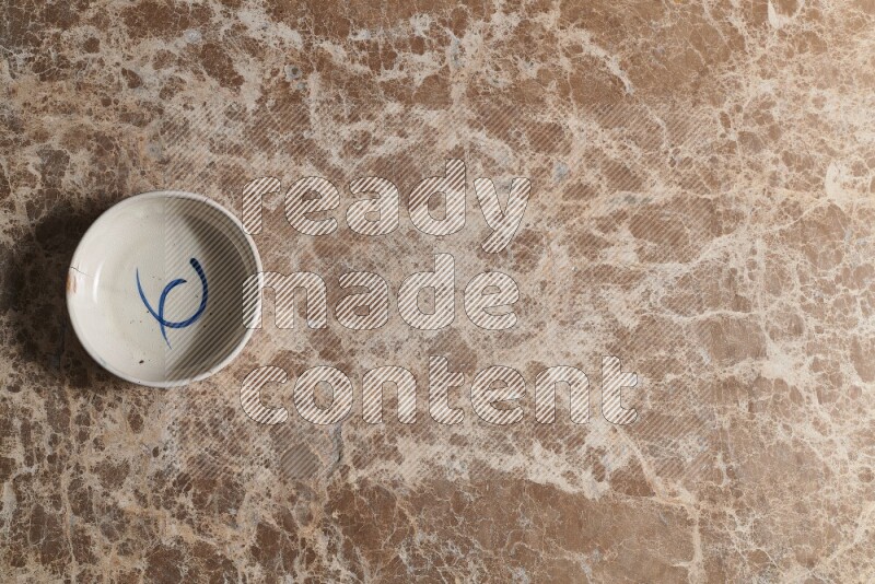 A multicolored pottery bowl on beige marble background