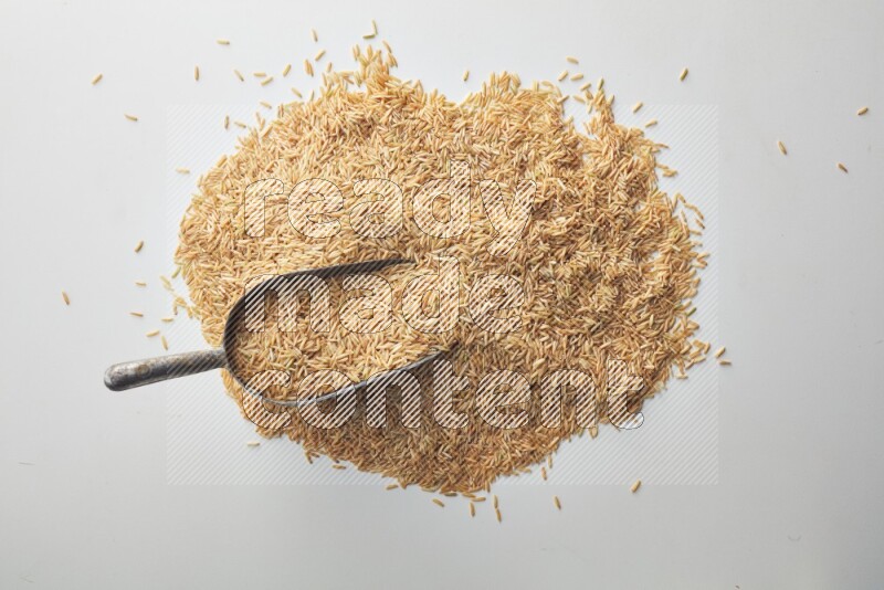 Top-view of a long grain brown rice, and shovel on white background