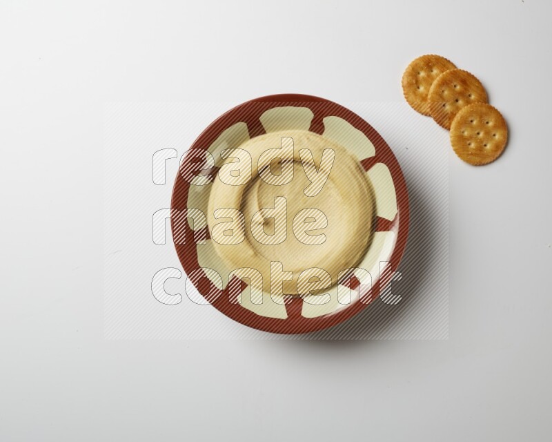 Plain hummus in a traditional plate on a white background
