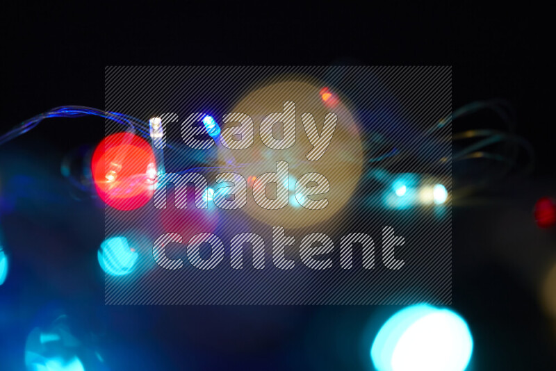 Light bulbs glowing against backdrop of multicolord bokeh