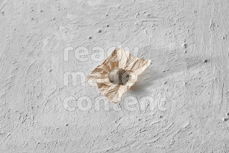 Black pepper powder on a crumpled paper on a textured white flooring