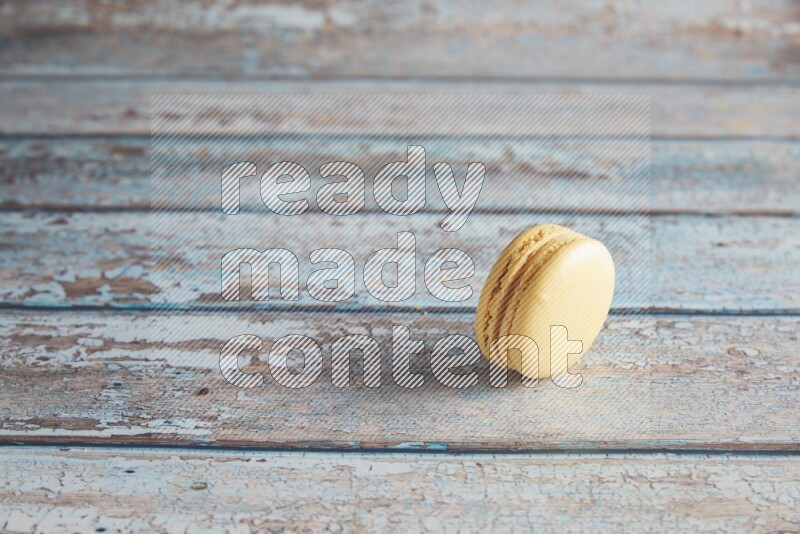 45º Shot of Yellow Vanilla macaron on light blue wooden background