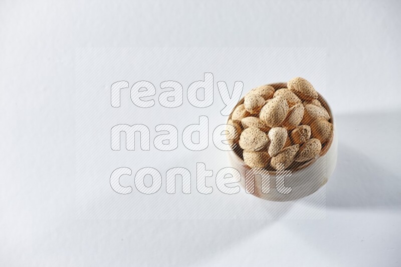 A beige ceramic bowl full of almonds on a white background in different angles