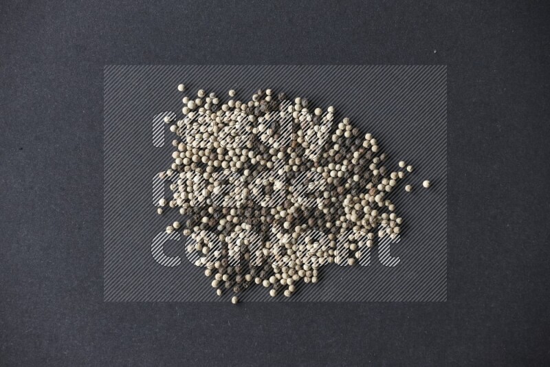 حبوب الفلفل المختلطة السوداء والبيضاء على أرضية سوداء