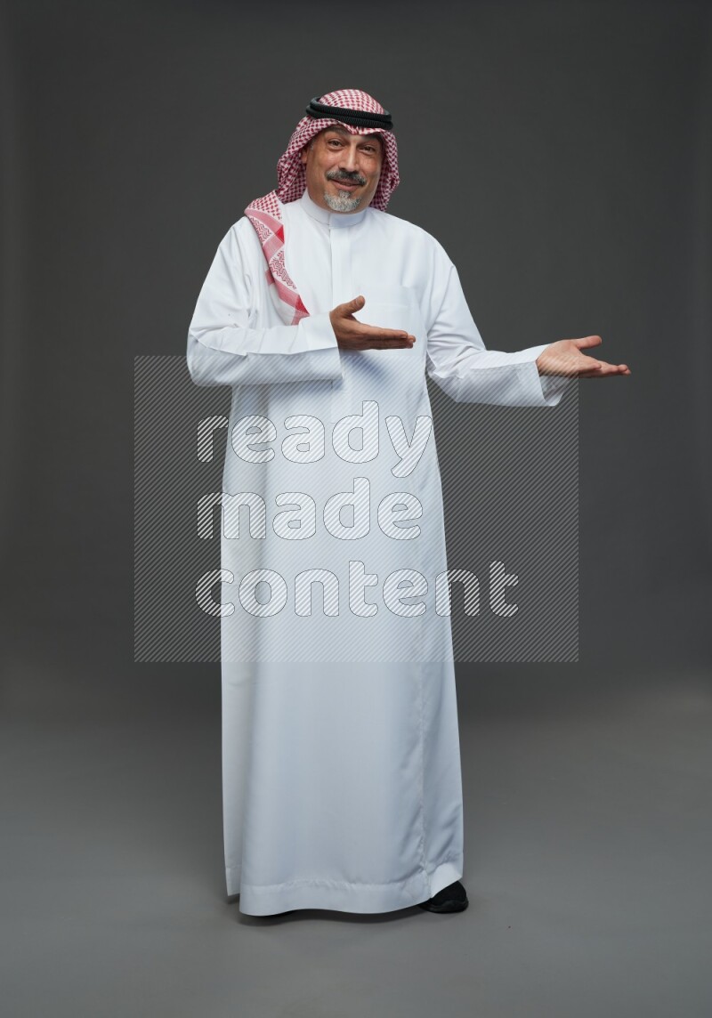 Saudi man with shomag Standing Interacting with the camera on gray background