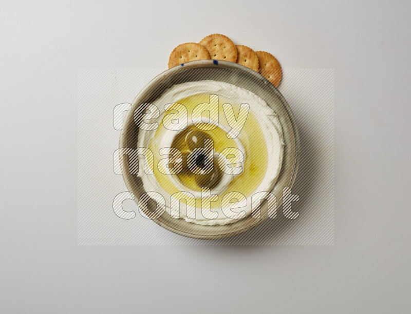 Lebnah garnished with whole olives in a grey pottery plate on a white background