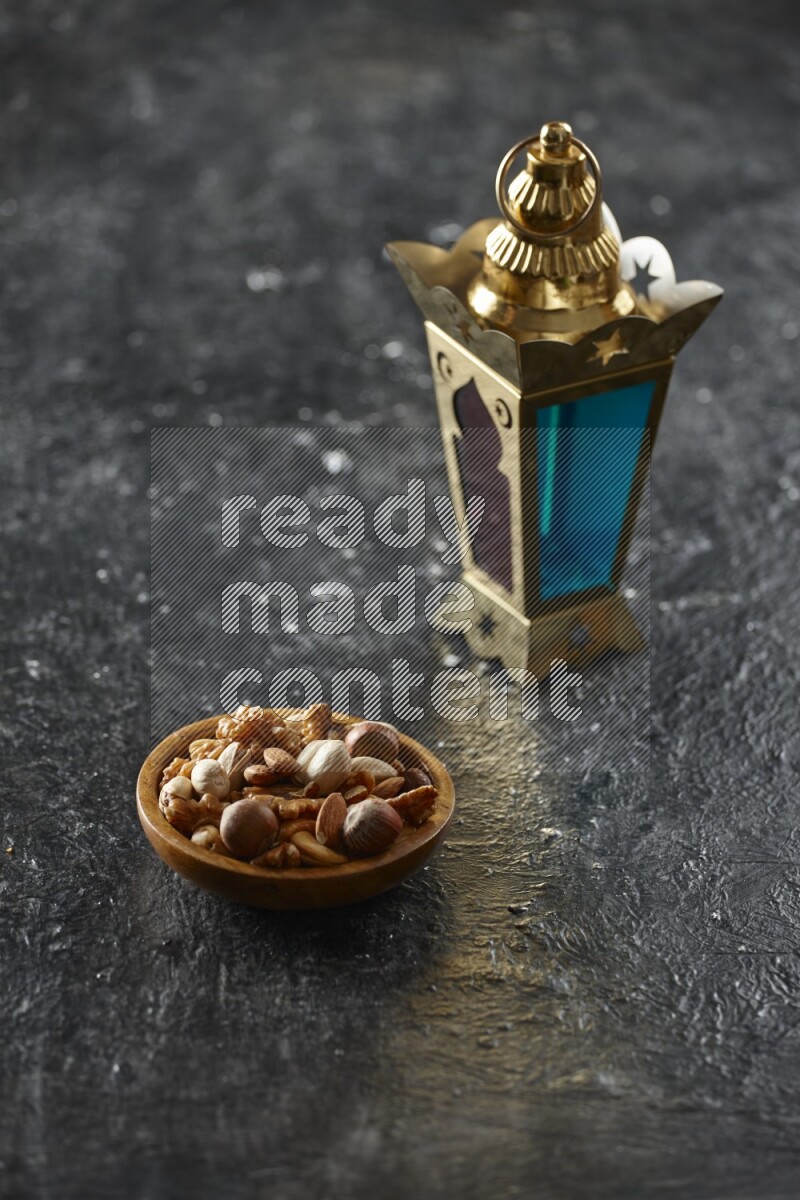 A golden lantern with different drinks, dates, nuts, prayer beads and quran on textured black background