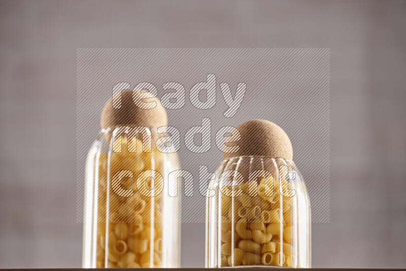 Raw pasta in glass jars on beige background