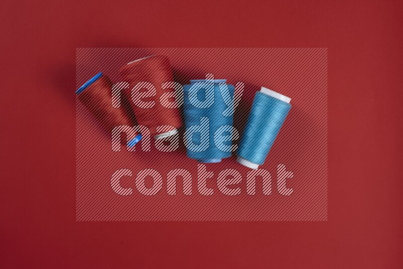 A blue and red collection of sewing and tailoring tools arranged on a red background