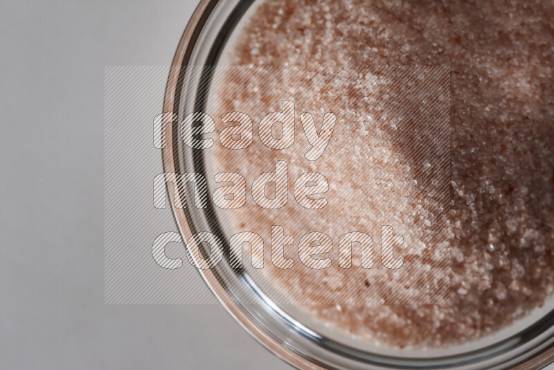 A glass bowl full of fine himalayan salt on white background