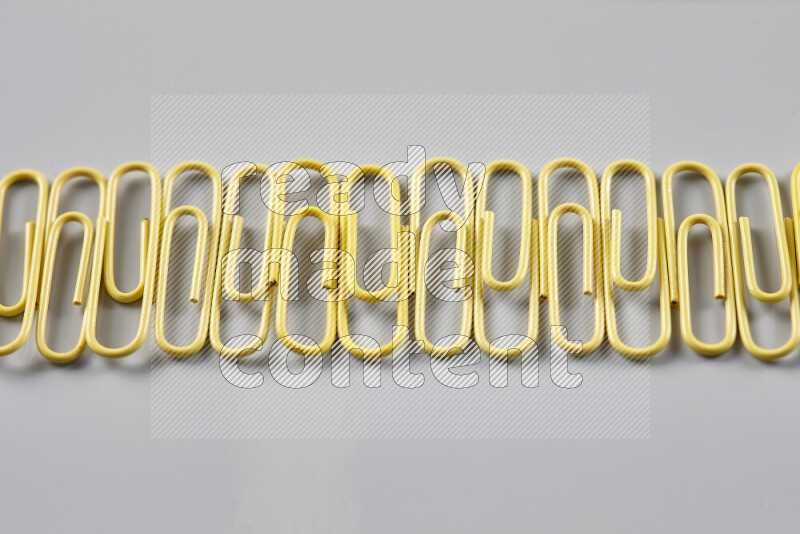 Yellow paper clips isolated on a grey background