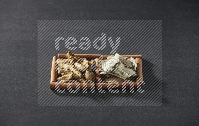 2 squares of cinnamon sticks full of bay laurel leaves and turmeric fingers on black flooring