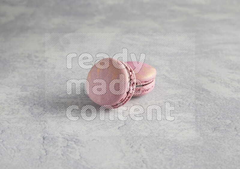 45º Shot of two Purple Strawberry macarons on white  marble background