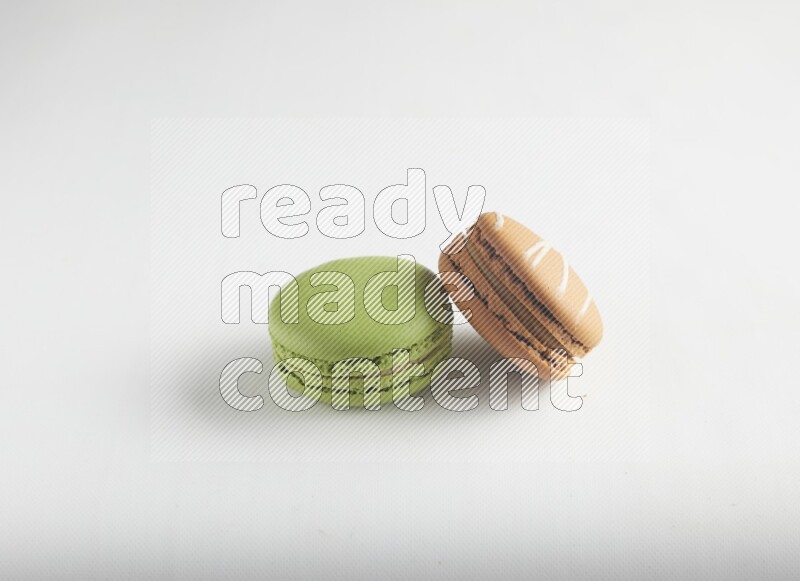45º Shot of of two assorted Brown Irish Cream, and Green Pistachio macarons on white background