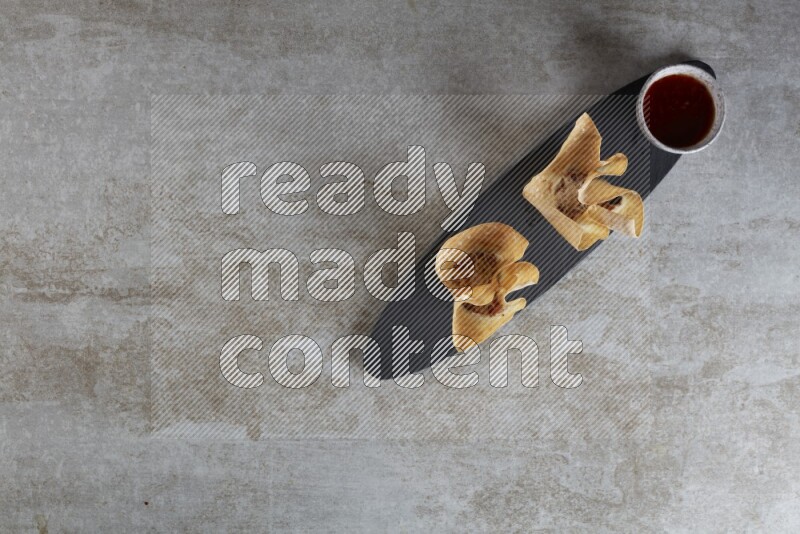 wonton cups with soy sauce ramkin on oval slate on grey textured counter top