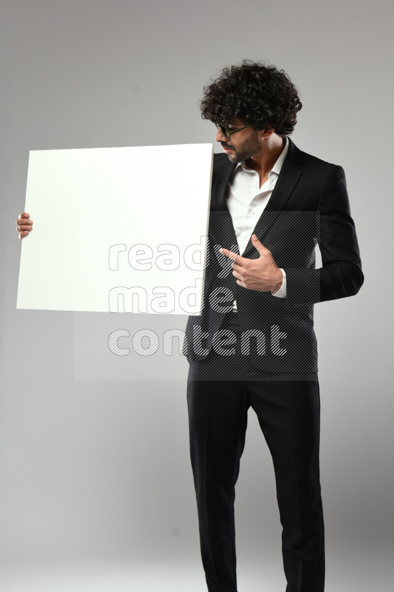 A man wearing formal standing and holding a white board on white background