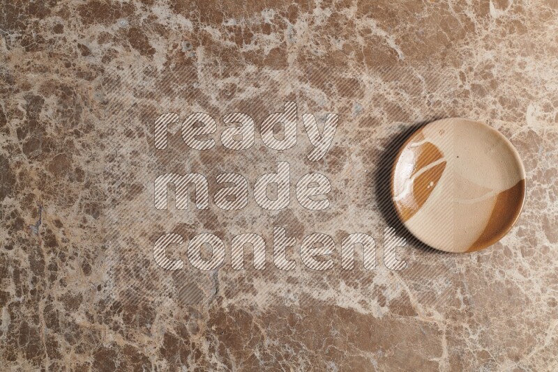 A multicolored pottery plate on beige marble background