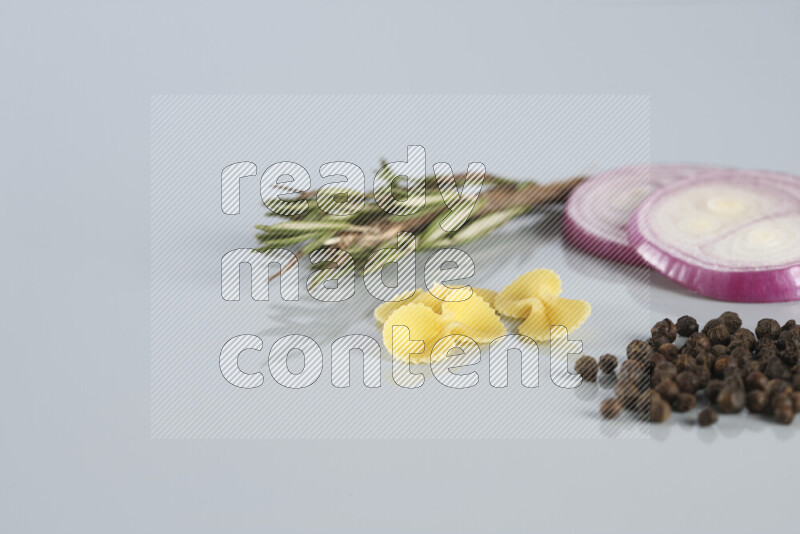 Raw pasta with different ingredients such as cherry tomatoes, garlic, onions, red chilis, black pepper, white pepper, bay laurel leaves, rosemary, cardamom and mushrooms on light blue background