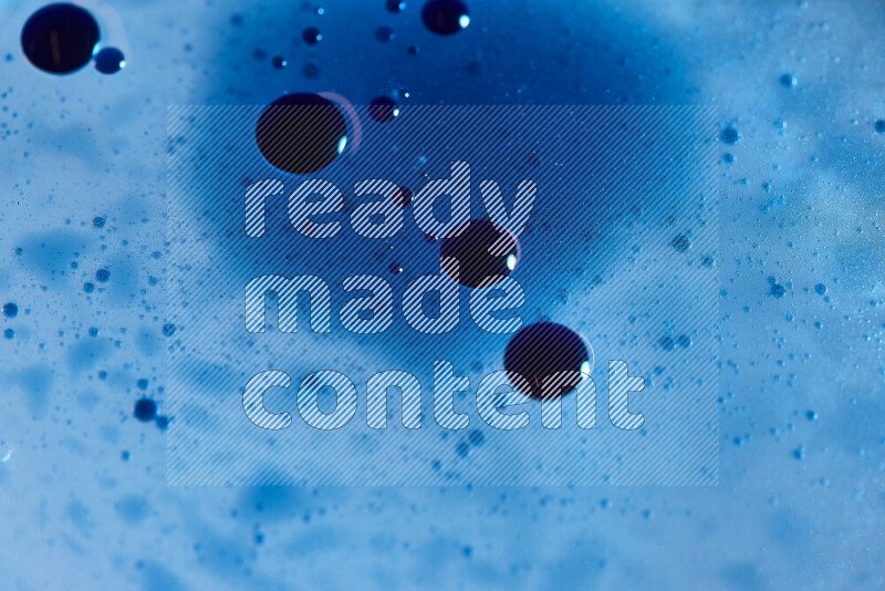 Close-ups of abstract blue watercolor drops on oil Surface on blue background