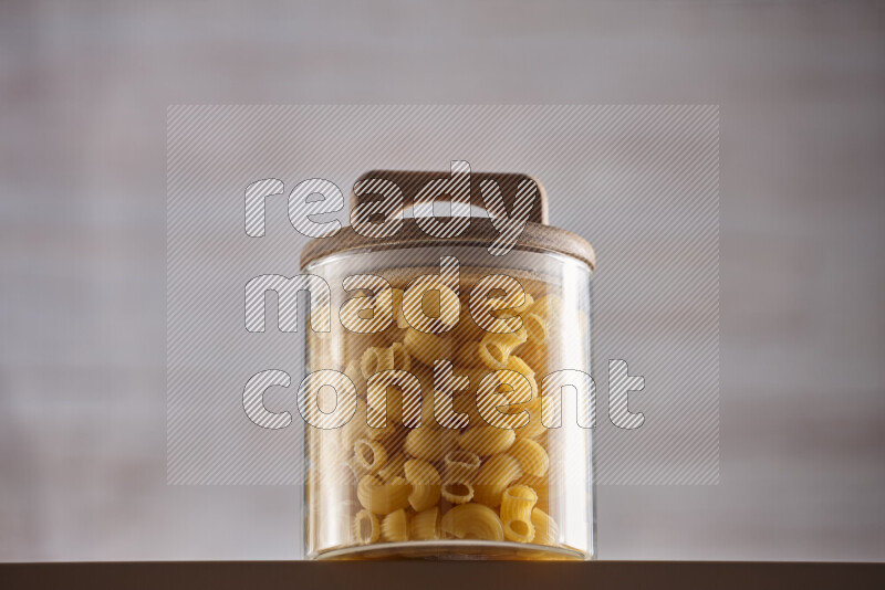 Raw pasta in glass jars on beige background