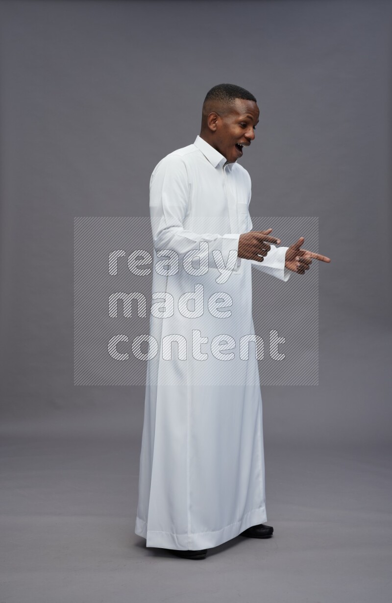 Saudi man wearing thob standing interacting with the camera on gray background