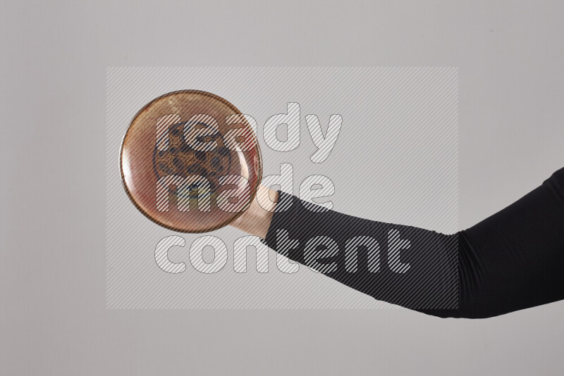A woman in black abaya holding different pottery essentials in different positions