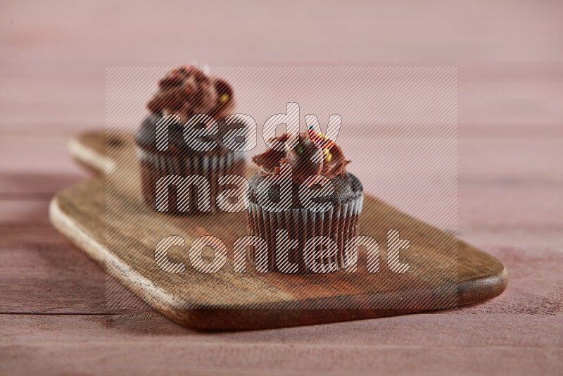 Chocolate mini cupcake topped with chocolate cream on a wooden board