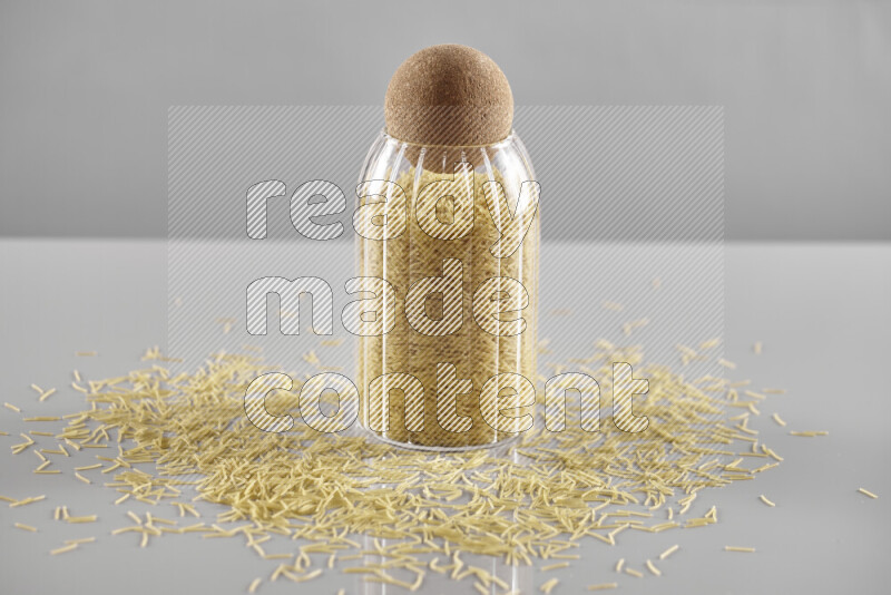 Raw pasta in a glass jar on light grey background