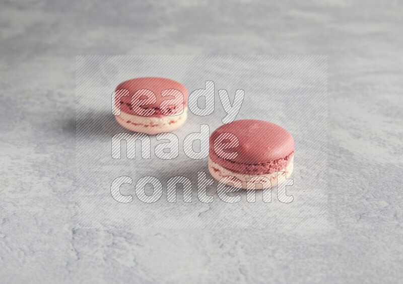45º Shot of two Pink Litchi Raspberry macarons  on white  marble background