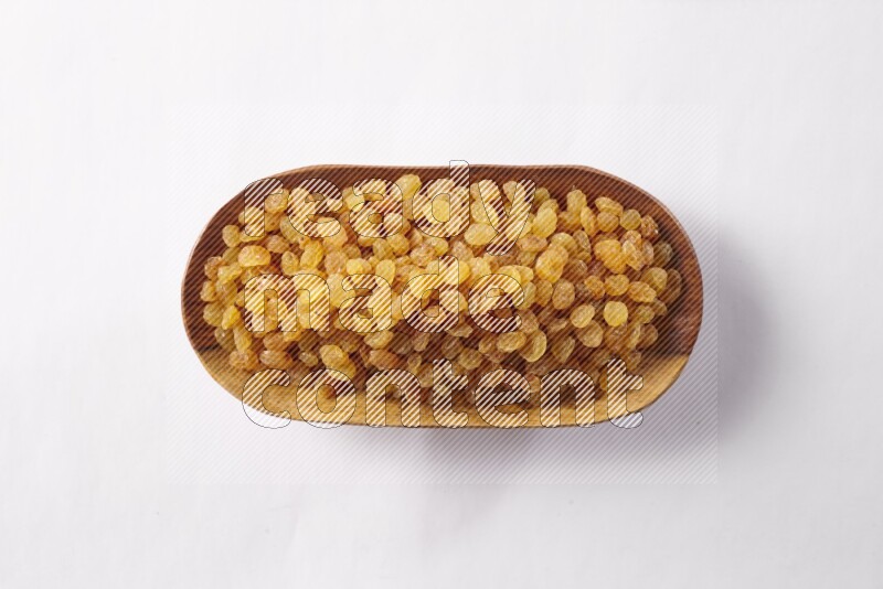 Raisins in a wooden plate on white background