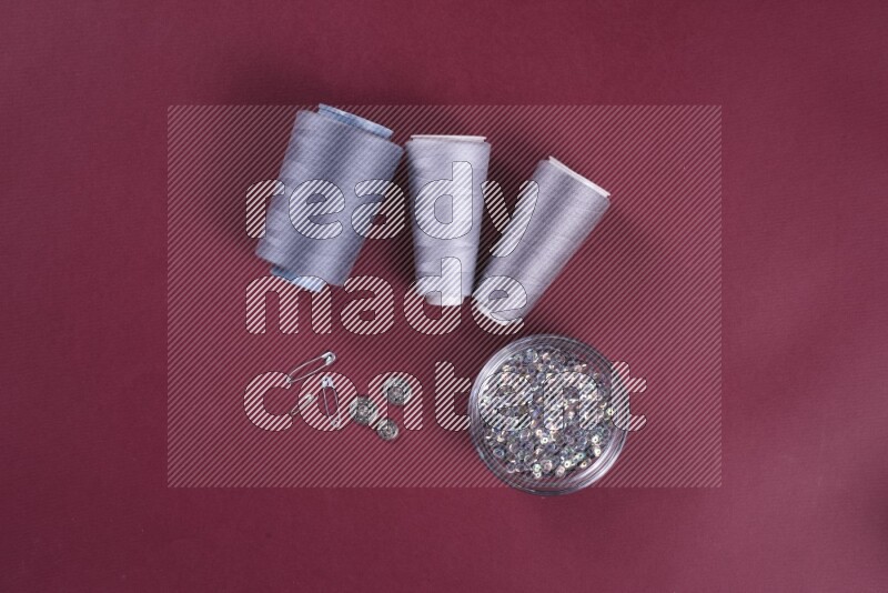 A grey collection of sewing and tailoring tools arranged on a red background