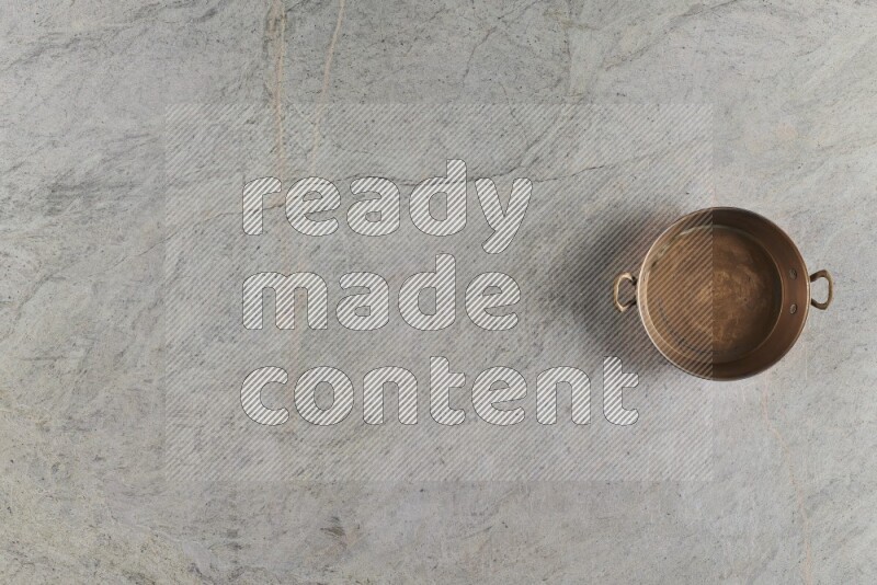 A small copper pan on grey marble background