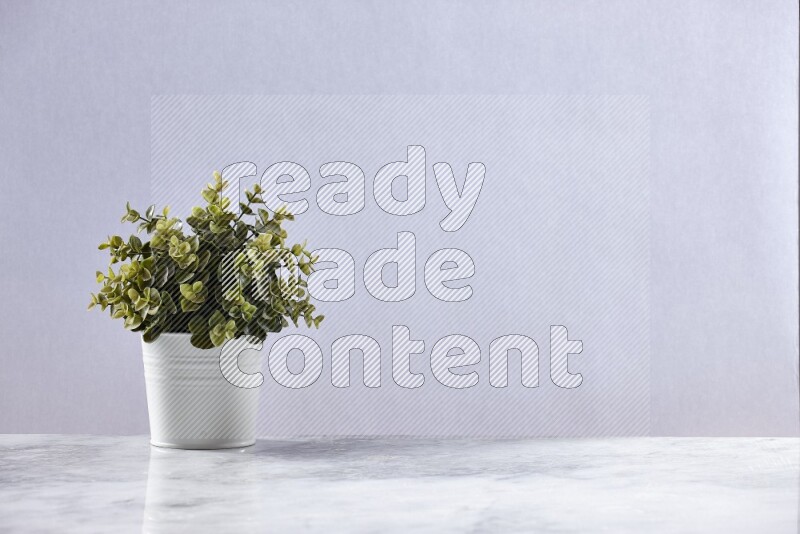 Green artificial plant in white pot on grey marble background