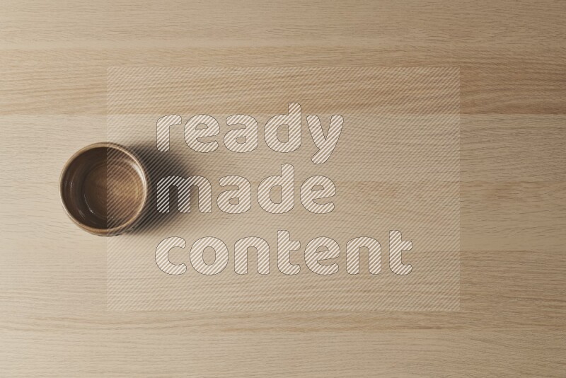 A beige pottery bowl on light wooden background