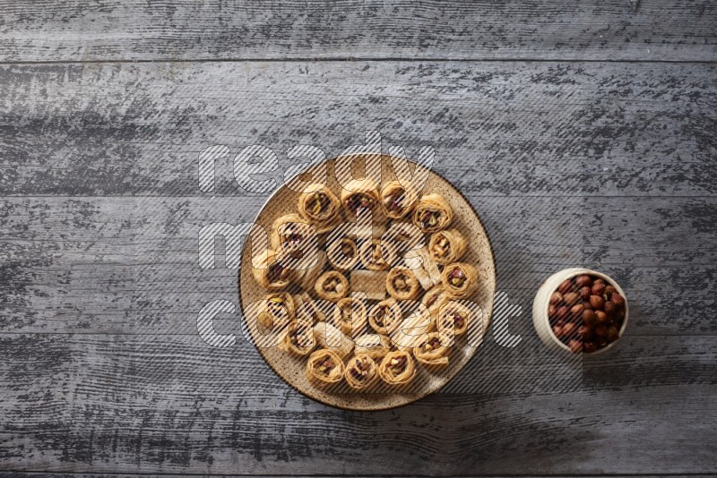 Oriental sweets in a pottery plate with nuts, coffee and honey in a dark setup