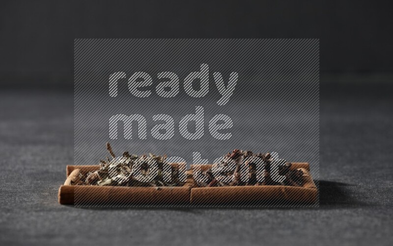 2 squares of cinnamon sticks full of cloves and dried basil on black flooring