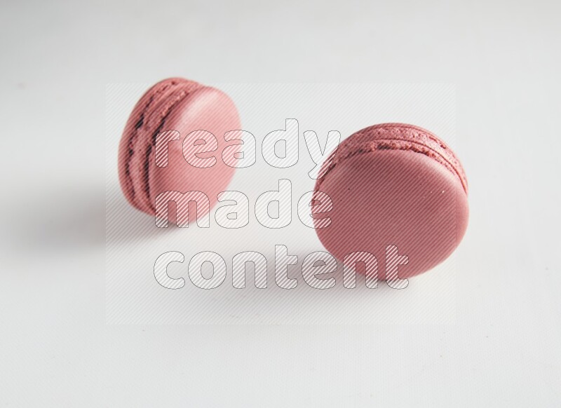 45º Shot of two Pink Raspberry macarons on white background