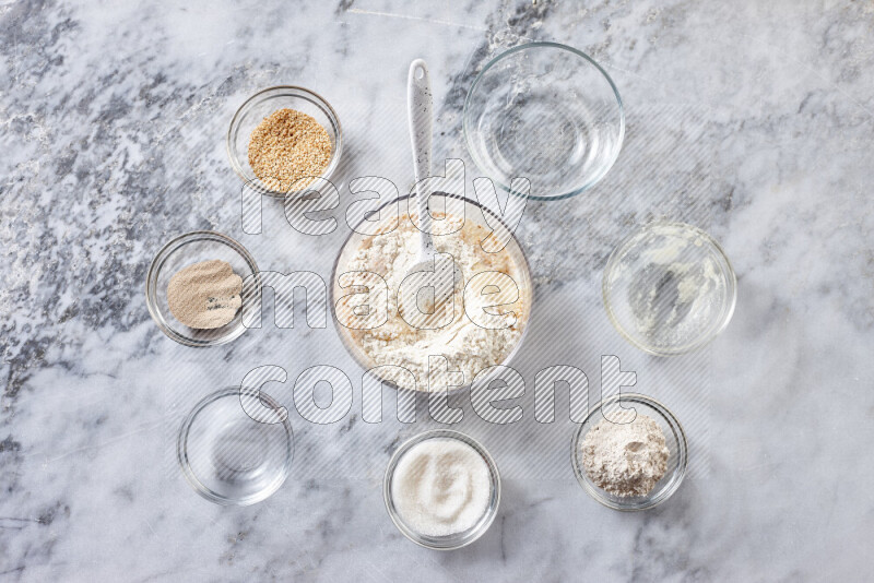 Kahk step by step with its ingredients ghee, sugar, flour, sesame, yeast, water and kahk flavor on grey marble background