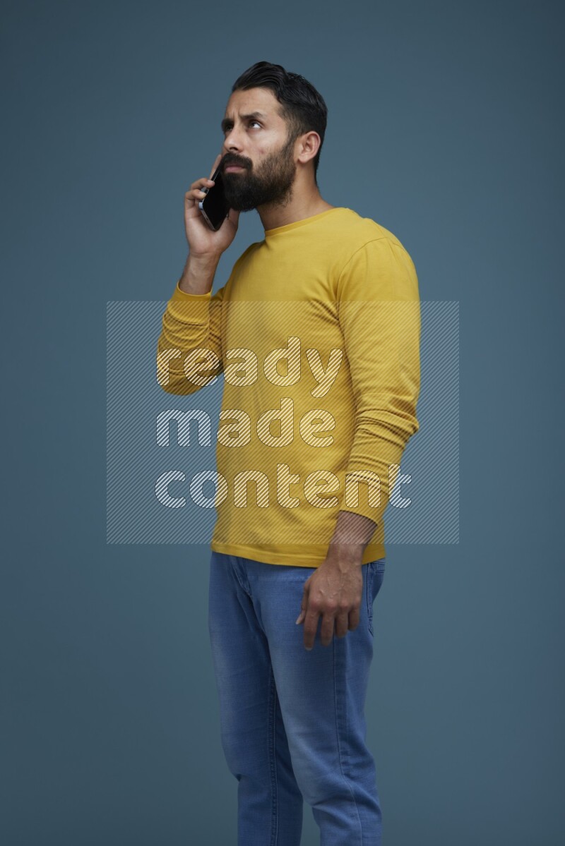 A man having a calling in a blue background wearing a yellow shirt