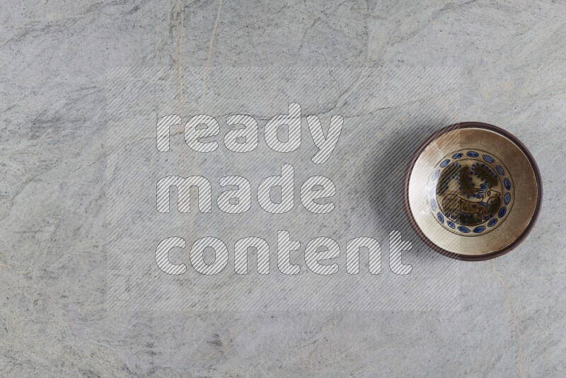 A decorative pottery plate on grey marble background