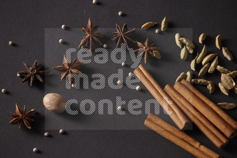 Cinnamon sticks, cardamom, star anise, nutmeg and white peppers on a black background