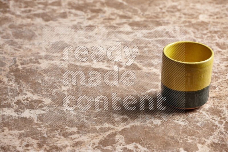 A multicolored pottery cup on beige marble background