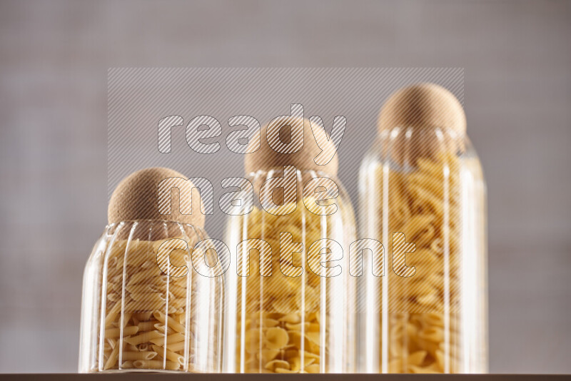 Raw pasta in glass jars on beige background