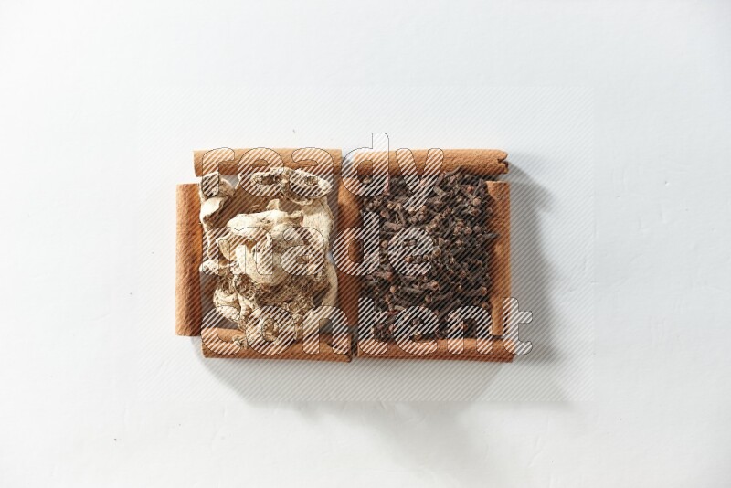 2 squares of cinnamon sticks full of cloves and dried ginger on white flooring