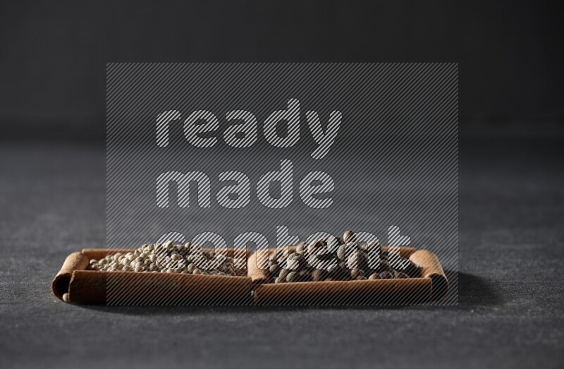 2 squares of cinnamon sticks full of white peppers and allspice on black flooring