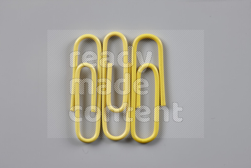 Yellow paper clips isolated on a grey background