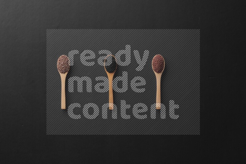 الفلفل الأسود وحبوب الخردل وحبة البركة وحب الرشاد والكمون و حبوب الكتان في معالق خشبية علي خلفية سوداء