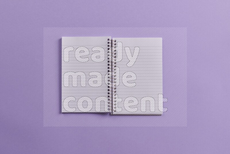 A blank open notebook with school supplies on purple background