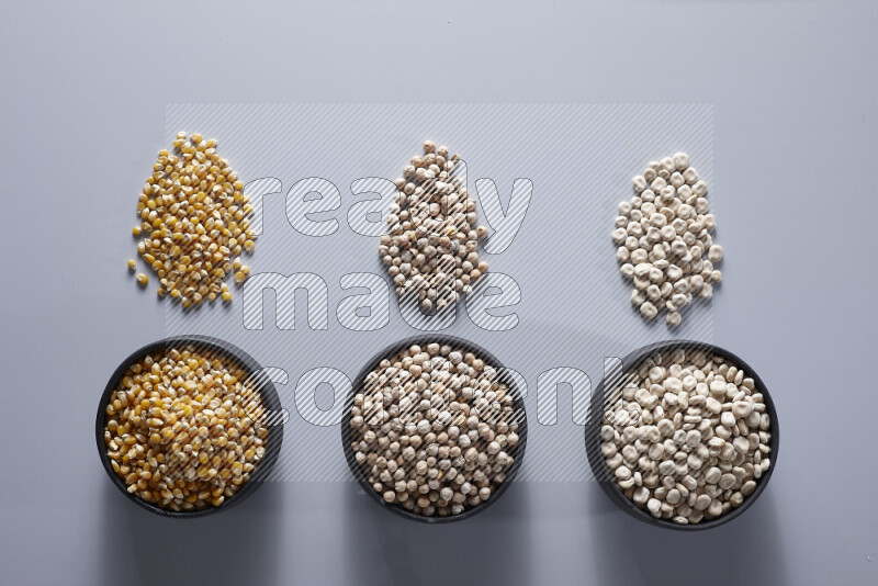 Legumes in pottery bowls on light grey background